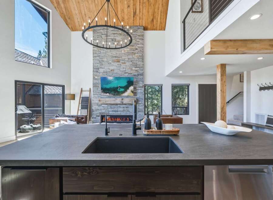 Experience luxury living in this stunning modern home featuring a grand stone fireplace and soaring vaulted ceilings with exposed wood beams.