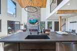 Experience luxury living in this stunning modern home featuring a grand stone fireplace and soaring vaulted ceilings with exposed wood beams.