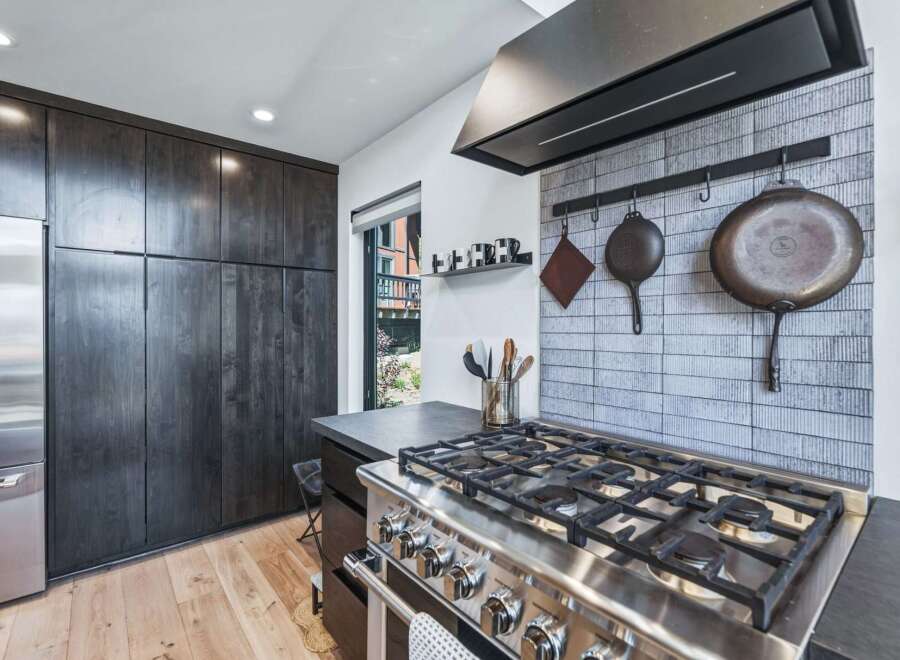 Experience culinary excellence in this modern kitchen, featuring a professional-grade gas range and a stylish tiled backsplash.