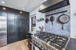 Experience culinary excellence in this modern kitchen, featuring a professional-grade gas range and a stylish tiled backsplash.