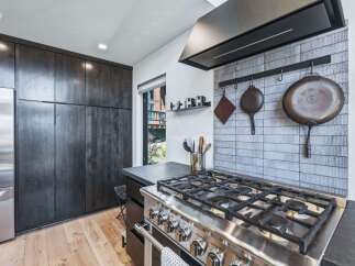 Experience culinary excellence in this modern kitchen, featuring a professional-grade gas range and a stylish tiled backsplash.