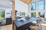Experience modern living in this stunning kitchen featuring a large island with a waterfall countertop, sleek dark cabinetry, and a professional-grade gas range.