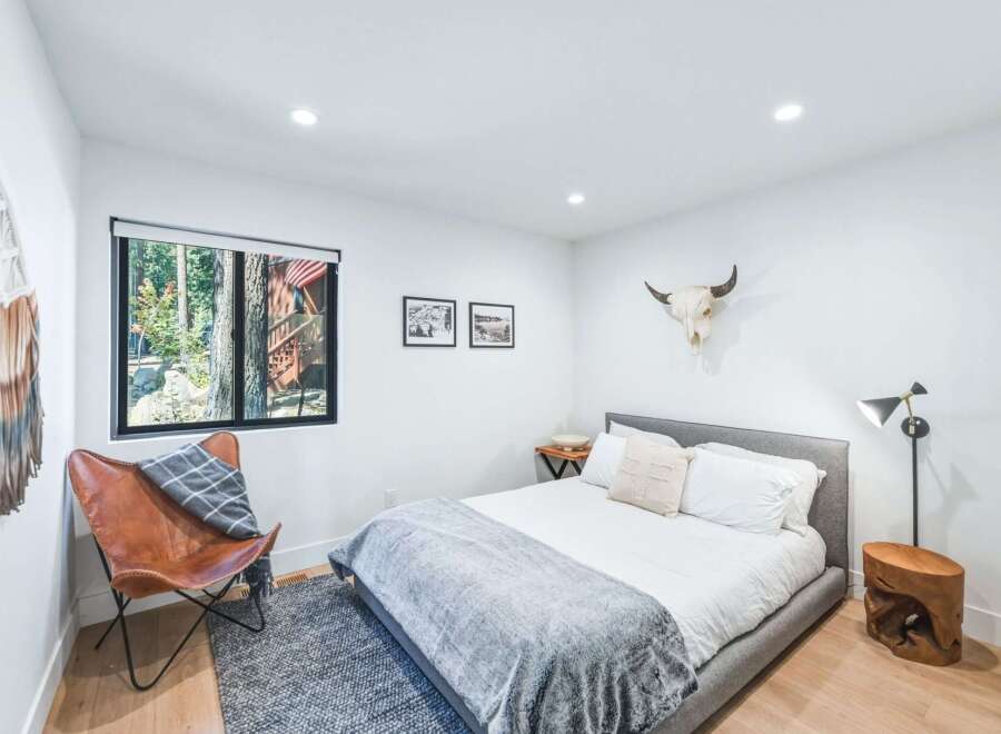 Experience rustic charm in this inviting bedroom, featuring a comfortable bed adorned with plush linens and a cozy grey throw.