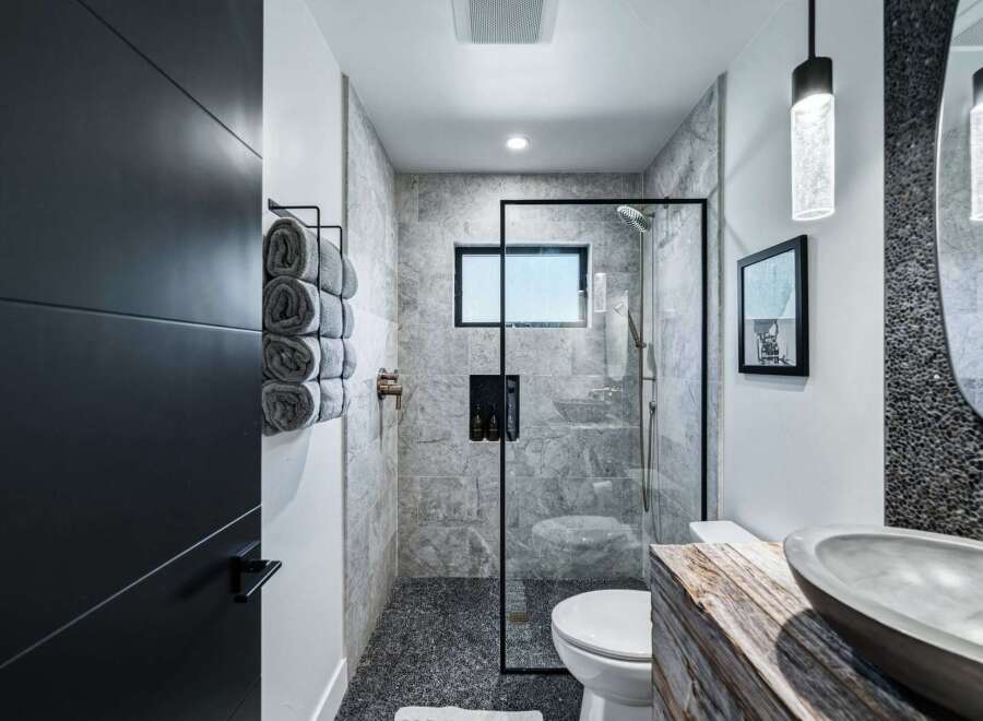 Experience modern luxury in this stunning bathroom featuring a sleek glass-enclosed shower with marble tile and a pebble-stone floor.