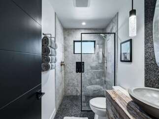 Experience modern luxury in this stunning bathroom featuring a sleek glass-enclosed shower with marble tile and a pebble-stone floor.