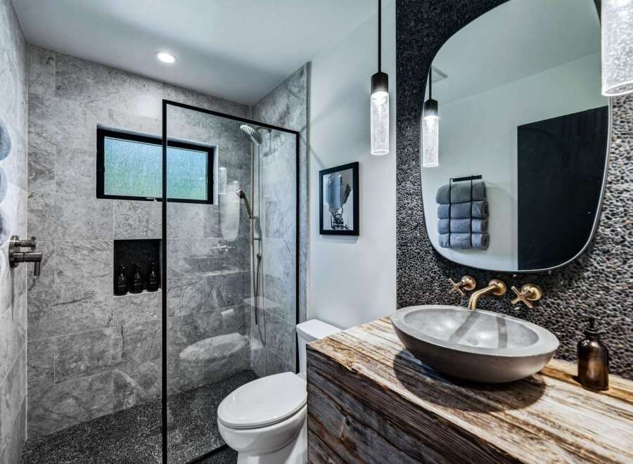 Experience modern luxury in this stunning bathroom featuring a sleek glass-enclosed shower with marble tile and a pebble-stone floor.