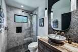 Experience modern luxury in this stunning bathroom featuring a sleek glass-enclosed shower with marble tile and a pebble-stone floor.