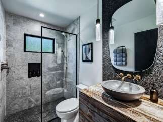 Experience modern luxury in this stunning bathroom featuring a sleek glass-enclosed shower with marble tile and a pebble-stone floor.