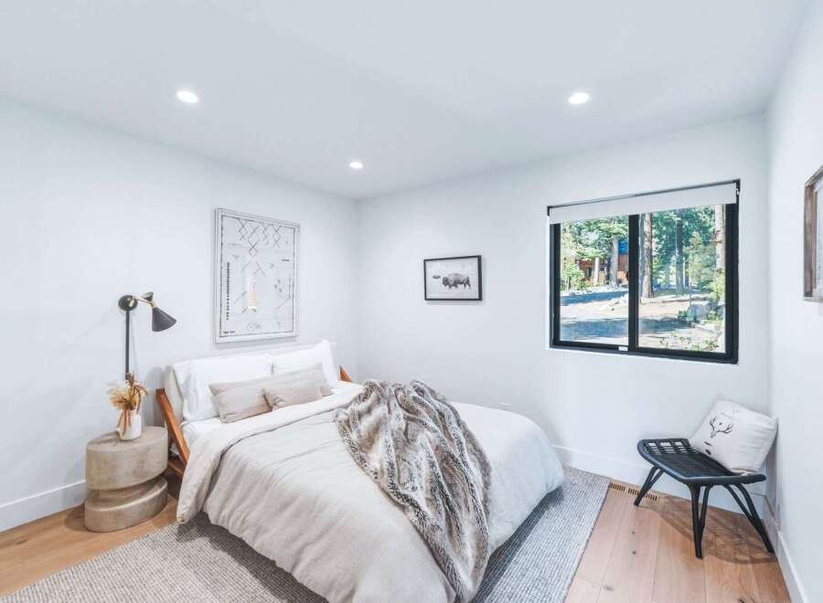 This modern bedroom features a comfortable queen-size bed with a plush throw, complemented by a stylish bedside lamp and a unique concrete side table.