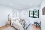 This modern bedroom features a comfortable queen-size bed with a plush throw, complemented by a stylish bedside lamp and a unique concrete side table.