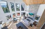 Experience breathtaking mountain views from this stunning modern living room, featuring a soaring vaulted ceiling with exposed wood beams and a dramatic floor-to-ceiling stone fireplace.