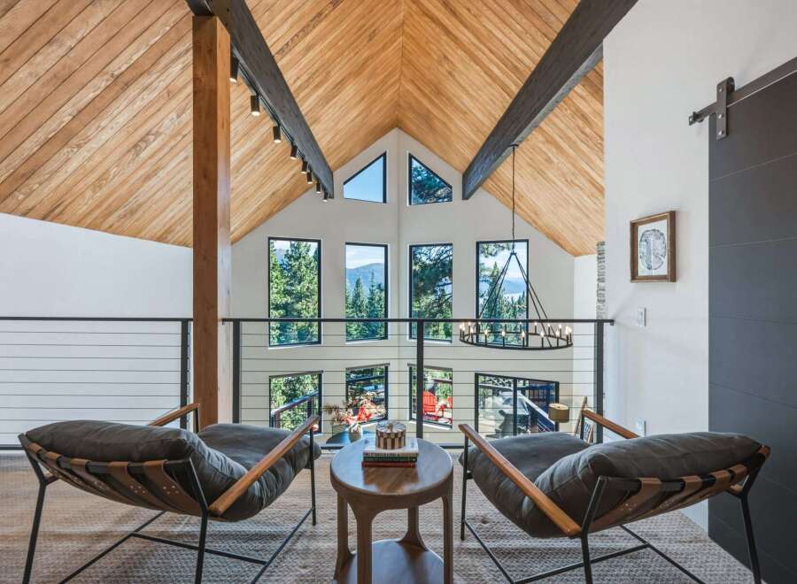 Experience breathtaking mountain views from this stunning modern home, featuring a soaring vaulted ceiling with exposed wooden beams and a wall of expansive windows.