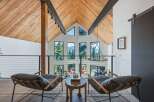 Experience breathtaking mountain views from this stunning modern home, featuring a soaring vaulted ceiling with exposed wooden beams and a wall of expansive windows.