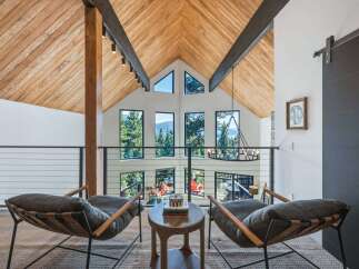 Experience breathtaking mountain views from this stunning modern home, featuring a soaring vaulted ceiling with exposed wooden beams and a wall of expansive windows.