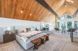 Experience luxury living in this stunning loft bedroom featuring a vaulted wood-paneled ceiling and expansive windows offering breathtaking mountain views.