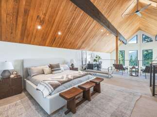 Experience luxury living in this stunning loft bedroom featuring a vaulted wood-paneled ceiling and expansive windows offering breathtaking mountain views.