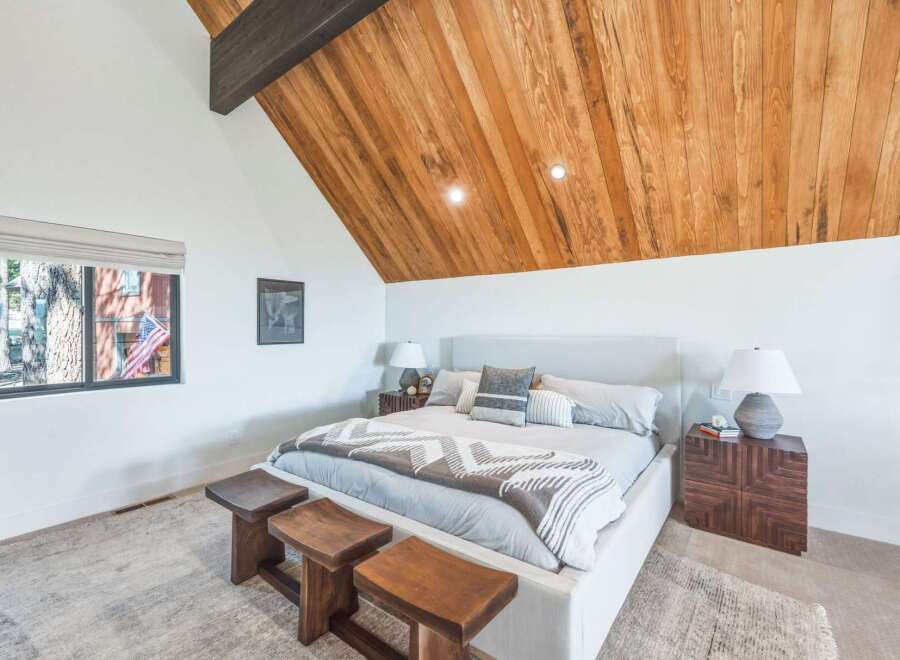 Experience rustic charm and modern comfort in this inviting bedroom, featuring a vaulted wood-paneled ceiling and a cozy king-sized bed.