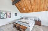 Experience rustic charm and modern comfort in this inviting bedroom, featuring a vaulted wood-paneled ceiling and a cozy king-sized bed.