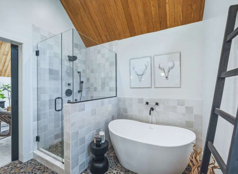 Experience modern luxury in this stunning bathroom, featuring a spacious glass-enclosed shower with sleek black fixtures and a freestanding soaking tub.