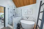 Experience modern luxury in this stunning bathroom, featuring a spacious glass-enclosed shower with sleek black fixtures and a freestanding soaking tub.
