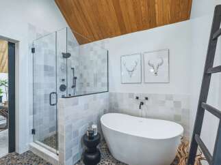 Experience modern luxury in this stunning bathroom, featuring a spacious glass-enclosed shower with sleek black fixtures and a freestanding soaking tub.