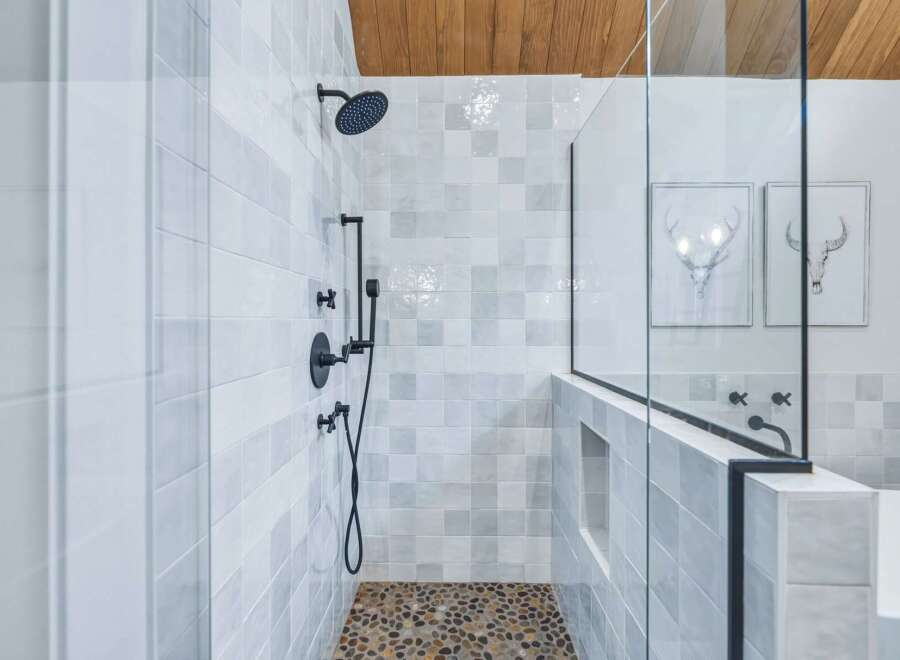 Experience modern luxury in this stunning bathroom featuring a spacious walk-in shower with elegant tilework and a unique pebble floor.