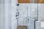 Experience modern luxury in this stunning bathroom featuring a spacious walk-in shower with elegant tilework and a unique pebble floor.