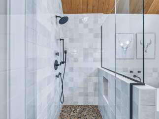 Experience modern luxury in this stunning bathroom featuring a spacious walk-in shower with elegant tilework and a unique pebble floor.