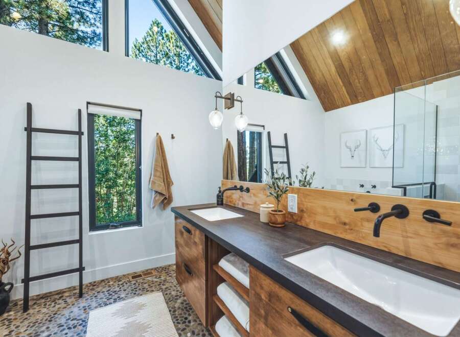 Experience modern luxury in this stunning bathroom, featuring a spacious double vanity with sleek black fixtures and warm wood accents.