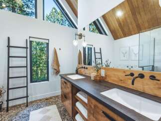 Experience modern luxury in this stunning bathroom, featuring a spacious double vanity with sleek black fixtures and warm wood accents.