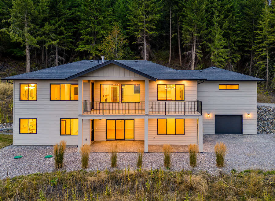 Experience modern living in this stunning two-story home nestled against a backdrop of lush evergreen trees.