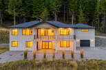 Experience modern living in this stunning two-story home nestled against a backdrop of lush evergreen trees.