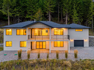 Experience modern living in this stunning two-story home nestled against a backdrop of lush evergreen trees.