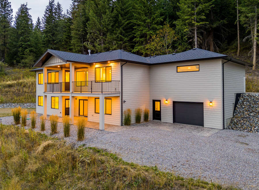 Discover this stunning modern home nestled against a backdrop of lush evergreen trees.