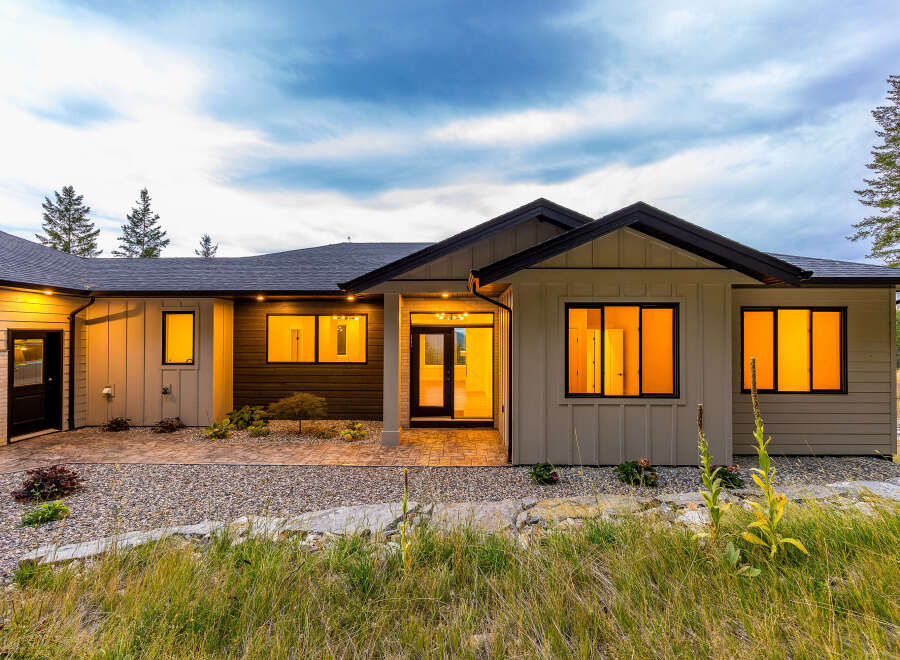 Experience modern living in this stunning home featuring a sleek exterior and warm, inviting interior illuminated by large windows.
