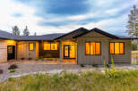 Experience modern living in this stunning home featuring a sleek exterior and warm, inviting interior illuminated by large windows.