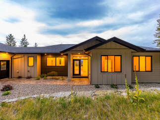 Experience modern living in this stunning home featuring a sleek exterior and warm, inviting interior illuminated by large windows.