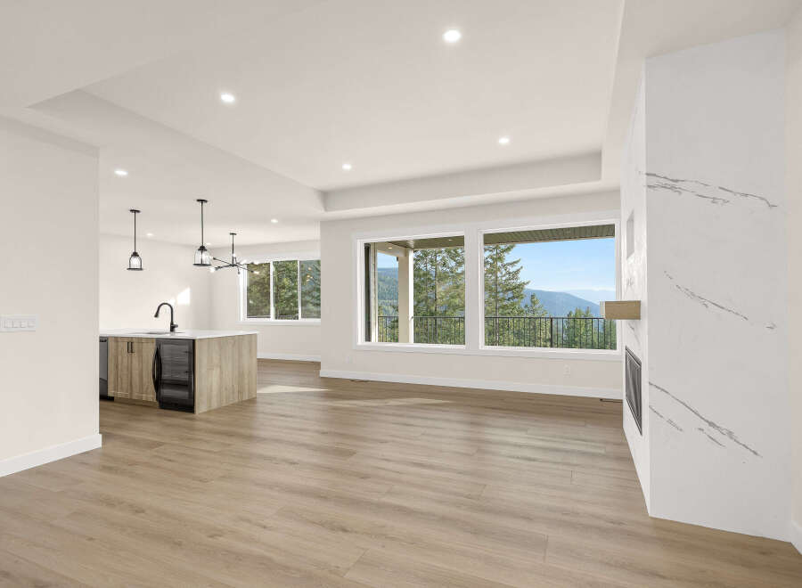 Experience breathtaking mountain views from this stunning open-concept living space, featuring a modern kitchen island with ample seating and a sleek fireplace.