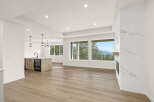 Experience breathtaking mountain views from this stunning open-concept living space, featuring a modern kitchen island with ample seating and a sleek fireplace.