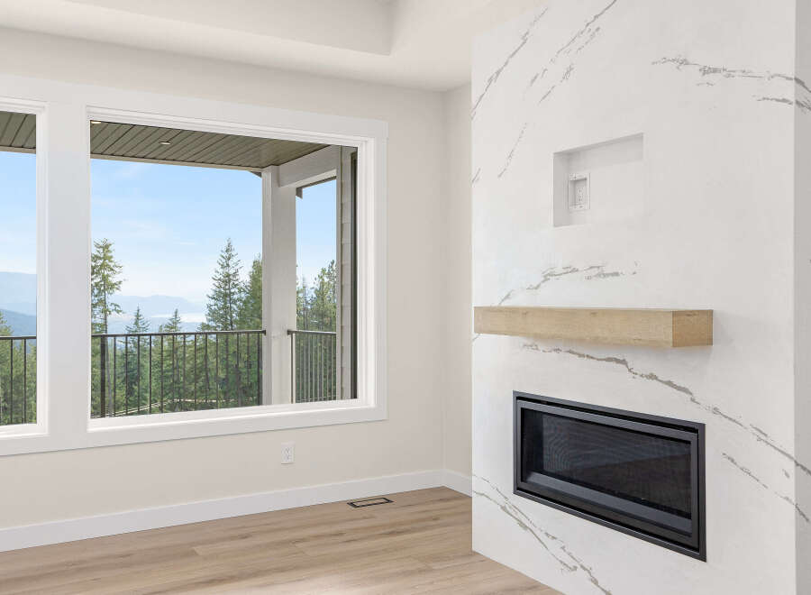 Experience breathtaking views from this stunning living space, featuring a modern fireplace with a natural wood mantle and a sleek marble-inspired surround.
