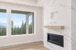 Experience breathtaking views from this stunning living space, featuring a modern fireplace with a natural wood mantle and a sleek marble-inspired surround.