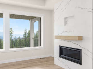 Experience breathtaking views from this stunning living space, featuring a modern fireplace with a natural wood mantle and a sleek marble-inspired surround.