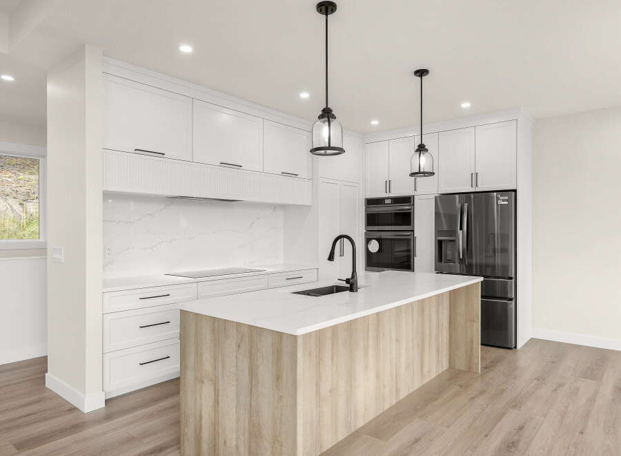 Experience modern luxury in this stunning kitchen, featuring sleek white cabinetry, a striking marble backsplash, and a spacious island with a natural wood finish.