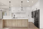 Experience modern luxury in this stunning kitchen, featuring a sleek island with a waterfall countertop and a warm wood base.