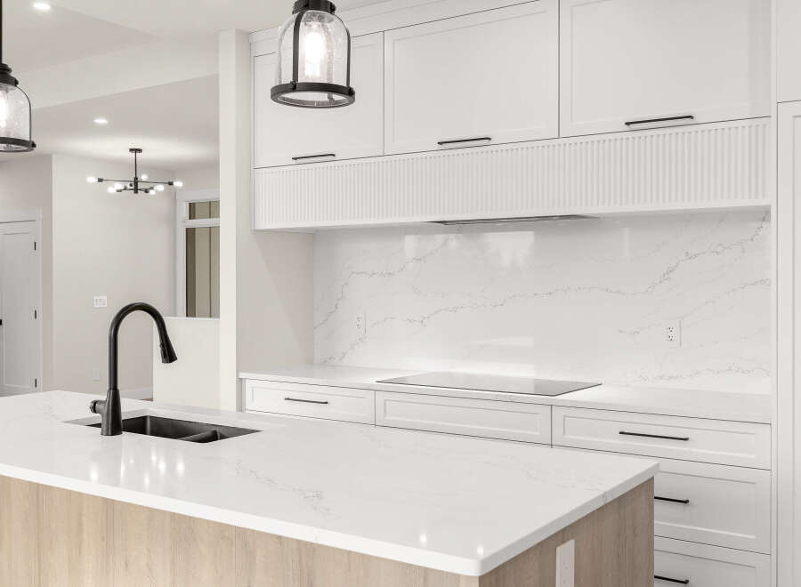 Experience modern luxury in this stunning kitchen, featuring sleek white cabinetry and a beautiful quartz countertop with a waterfall edge.