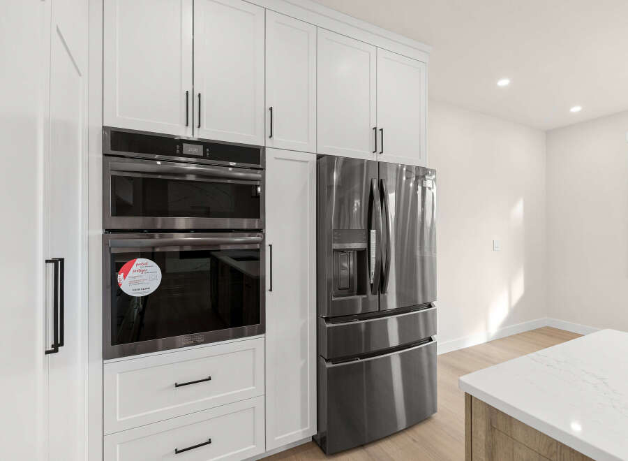 Experience modern luxury with this stunning kitchen featuring sleek, built-in stainless steel appliances, including a double oven and a French door refrigerator.