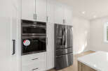Experience modern luxury with this stunning kitchen featuring sleek, built-in stainless steel appliances, including a double oven and a French door refrigerator.