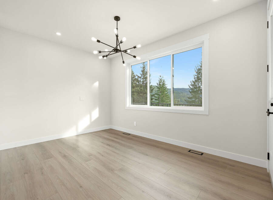Experience breathtaking views from this spacious room, featuring a large picture window that frames a stunning landscape of rolling hills and lush trees.