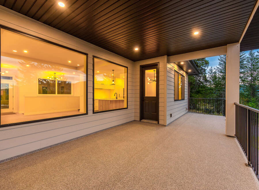 Experience luxurious indoor-outdoor living with this stunning covered patio, featuring expansive windows that offer breathtaking views of the surrounding forest.