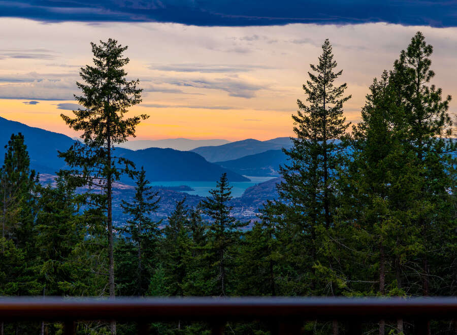 Experience breathtaking sunset views from this stunning property, nestled amidst lush evergreen trees.